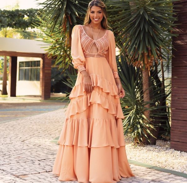 VESTIDO LONGO SALMON COM SAIA FLUIDA EM BABADOS ASSIMÉTRICOS E BLUSA EM RENASCENÇA NA MESMA COR. MANGAS BUFANTES DE TECIDO FLUIDO COM PUNHOS EM RENASCENÇA.